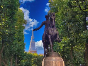 a statue of a person riding a horse next to a tree