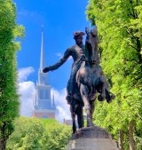 a statue of a man riding a horse next to a tree