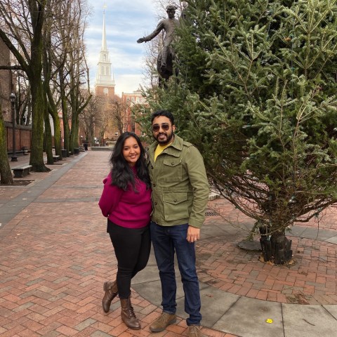 a person standing on a sidewalk next to a tree